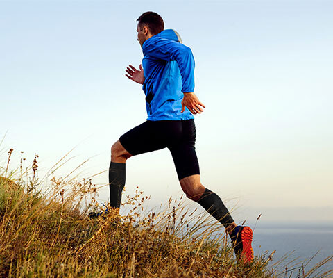 A man is seen running on a hilltop with a calf sleeve