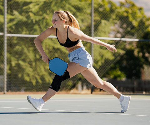 A woman playing pickleball while wearing a knee compression sleeve