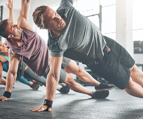 A diverse group of people doing yoga in a gym wearing wrist wraps