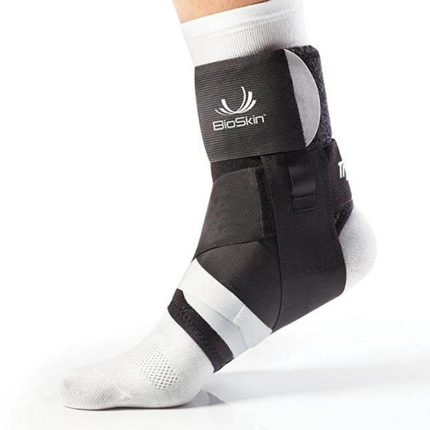 BioSkin TriLok ankle brace on right foot over white sock, with figure-eight straps for lateral support.