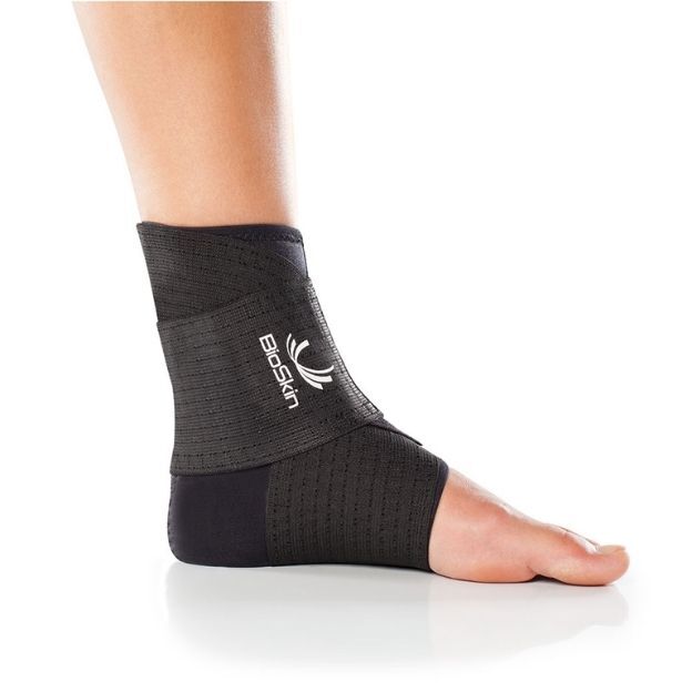 BioSkin ankle support sleeve in black on a bare left foot, provides stabilizing compression.