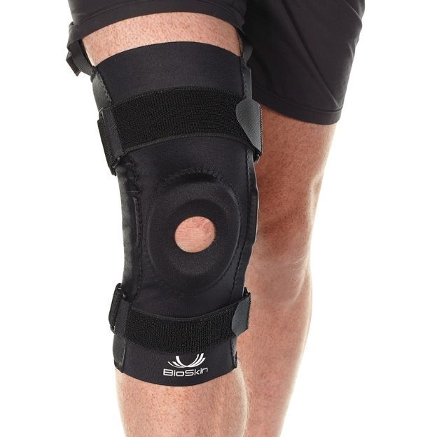 BioSkin hinged knee sleeve with open kneecap design and adjustable straps worn on a leg.