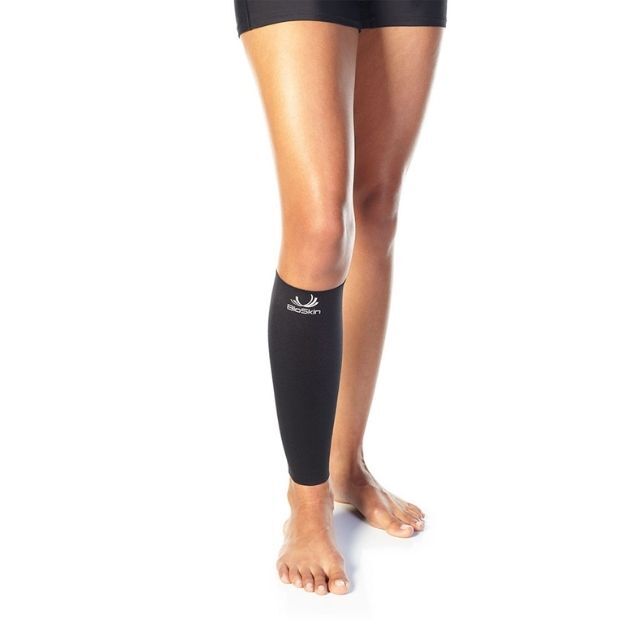 Model shows a black calf support sleeve on the lower leg and shin, worn barefoot against a clean white backdrop.