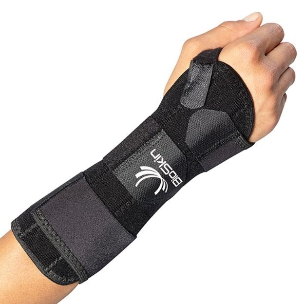 Hand wearing a black BioSkin DP3 Cock-Up Wrist Splint with loop strap and Velcro closures on a white background.