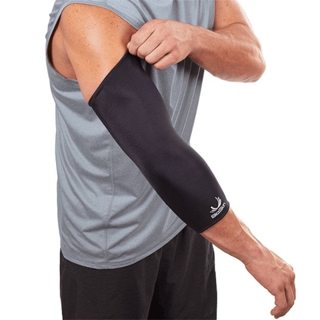 Person adjusts black BioSkin elbow compression sleeve on forearm and arm, wearing gray sleeveless shirt.
