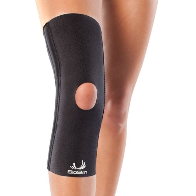 Black BioSkin knee sleeve with open-patella design on a model’s leg, providing compression support.