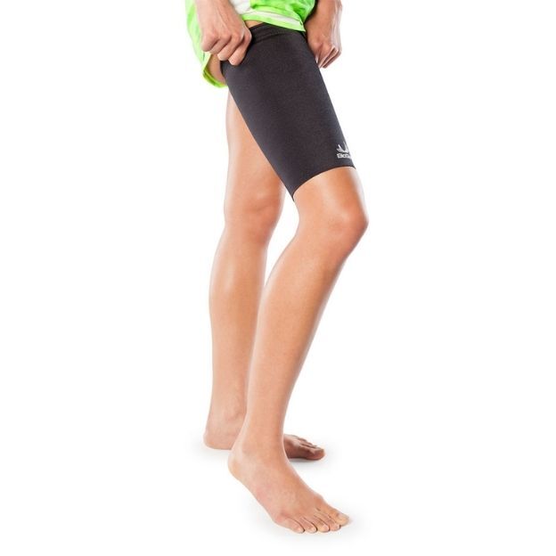 Person wearing a black thigh compression sleeve on the upper leg, pulling it into place; barefoot on white background.